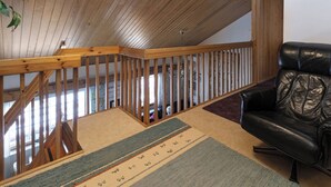Un escalier en bois mène à un espace de vie comprenant un canapé en cuir et un tapis à motifs.
