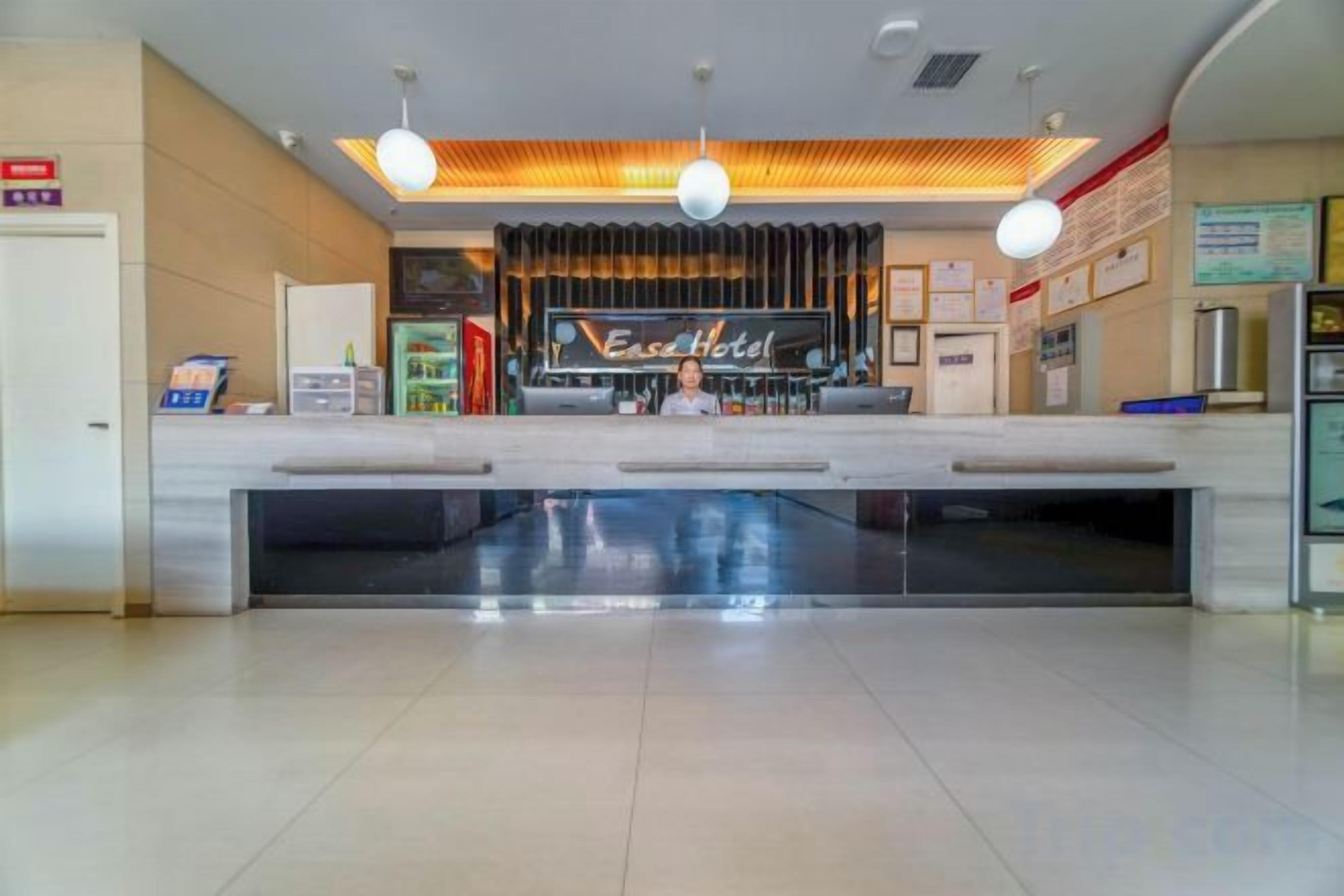 A hotel reception area with a counter, a television screen, and a sign that reads 'East Hotel.'