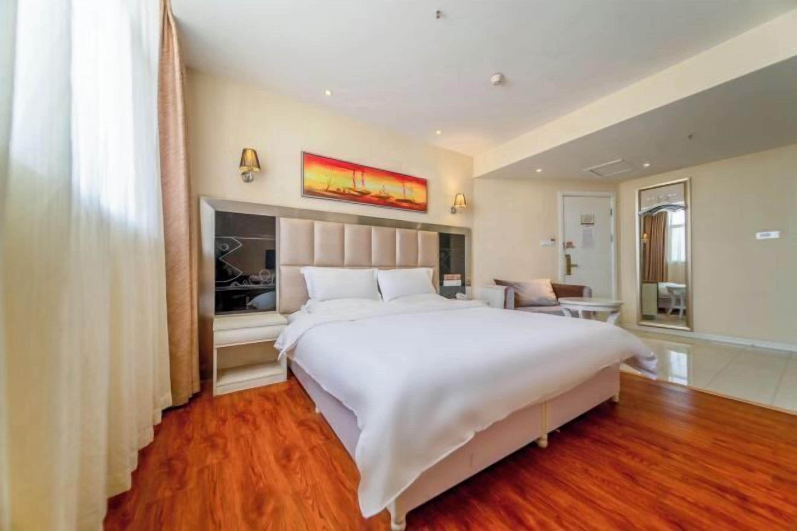 Una camera spaziosa con un letto grande, un armadio, uno specchio e un quadro appeso al muro.