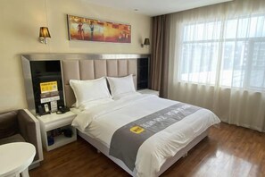 A hotel room with a bed, a desk, a chair, a nightstand, and a window with curtains. - MengDao Holiday Hotel(Yichang China Three Gorges University) (Yichang)