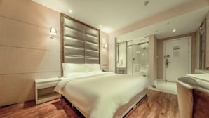 A modern hotel room with a large bed, bedside tables, a mirror, and a shower area. - MengDao Holiday Hotel(Yichang China Three Gorges University) (Yichang)