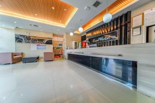 Zona de recepción de hotel con mostrador, área de estar y un amplio ventanal.