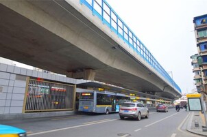 Una calle con parada de autobús, paso de peatones y un edificio en construcción.