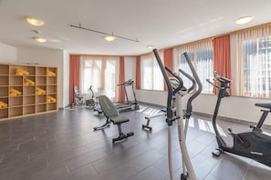 A gym with treadmills, a bench, and a wall of neatly folded towels. - Alpenblick Wellness Hotel (Fieschertal)