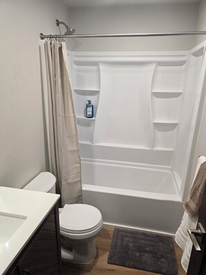 A bathroom with a toilet, a shower with a curtain, a sink, and a bottle of hand soap. - Brand new peaceful 3-bedroom townhome with AC in charming Helena (Helena)