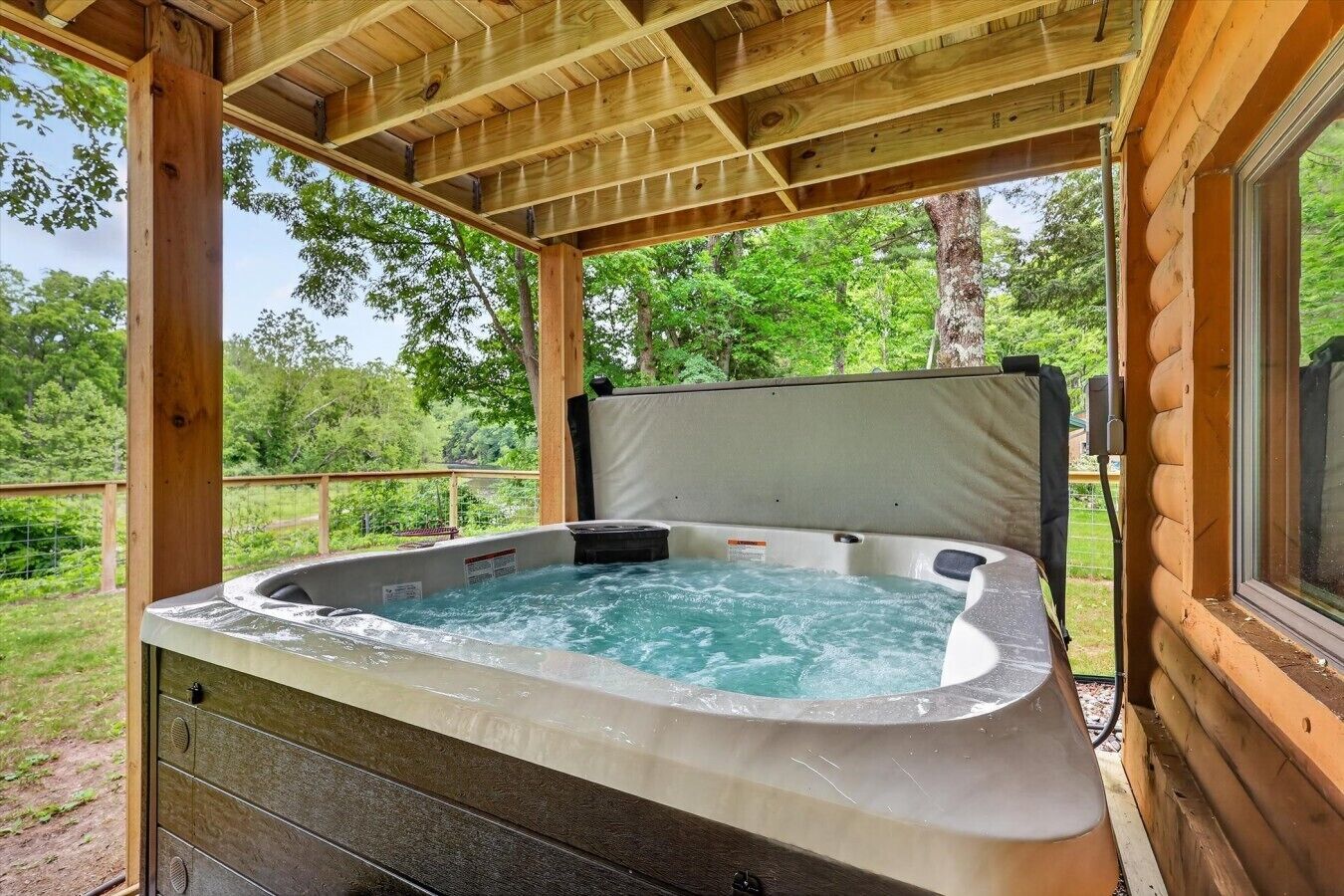 A hot tub in a wooden cabin with a view of the surrounding forest.