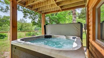 A hot tub in a wooden cabin with a view of the surrounding forest.
