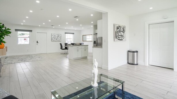A spacious living area with a glass coffee table, a white statue, and a kitchen in the background. - Spacious 4-bedroom house  with AC  15 minutes from Miami airport/ 14 ppl (Miami)