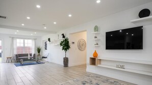 A modern living room with a flat-screen TV, a sofa, a coffee table, and a potted plant. - Spacious 4-bedroom house  with AC  15 minutes from Miami airport/ 14 ppl (Miami)