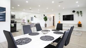 A modern kitchen with white cabinets, a built-in oven, and a dining area with a white table and black chairs. - Spacious 4-bedroom house  with AC  15 minutes from Miami airport/ 14 ppl (Miami)