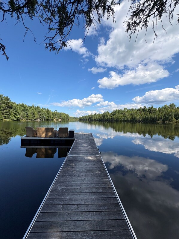 A wooden dock extending into calm water with a clear sky above.