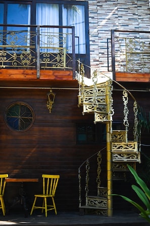 Ein Holzgebäude mit Wendeltreppe, einem Fenster mit Buntglasdekor und zwei gelben Stühlen.