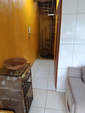 A corridor with a staircase, a wicker basket on a table, and a sofa. - Residencial Sabor da Bahia 
 Castelo Dourado
Aceita animais de estimação (Rio de Janeiro)