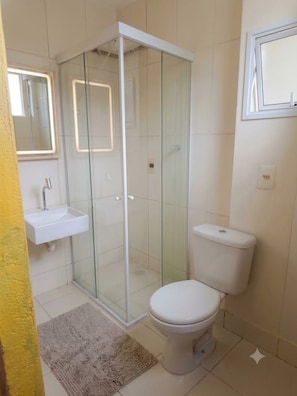 A bathroom with a glass-enclosed shower, a white sink, and a toilet. - Residencial Sabor da Bahia 
 Castelo Dourado
Aceita animais de estimação (Rio de Janeiro)
