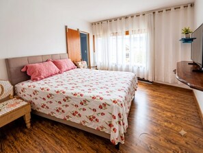 A bedroom with a bed, a wooden floor, a chair, a desk, and a television. - Residencial Sabor da Bahia 
 Castelo Dourado
Aceita animais de estimação (Rio de Janeiro)