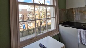 Eine Küche mit Fenster, einem weißen Tisch und einer Fernbedienung darauf.