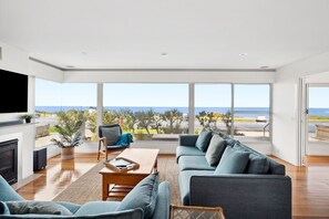 A spacious living room with a large window overlooking a scenic view. - Front Row Seats on the Esplanade (Torquay)