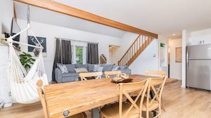 Eine moderne Küche mit einem Holzespeisebereich, Sesseln, einer Hängematte, einem grauen Sofa und einer Treppe.