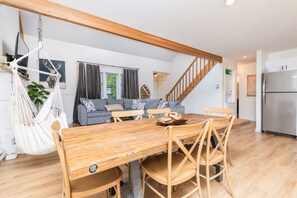 Eine moderne Küche mit einem Holzespeisebereich, Sesseln, einer Hängematte, einem grauen Sofa und einer Treppe.