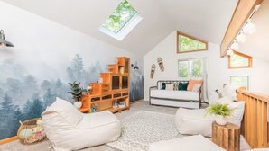 Ein gemütliches Zimmer mit Schlafkoje, einem weißen Sofa, einem Holzregal und einem großen Fenster.