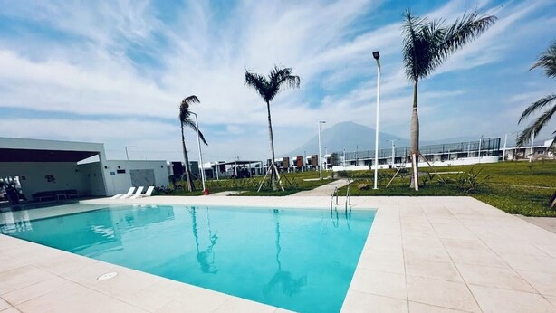 Una piscina con pavimento piastrellato, palme e montagne sullo sfondo.
