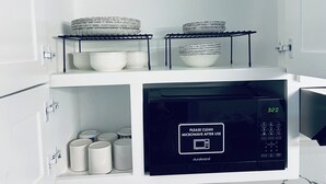 Una cucina con un forno a microonde, piatti, ciotole e barattoli impilati.