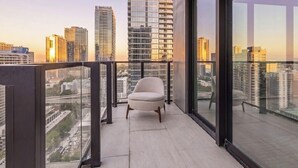 Un balcon avec une chaise, une vue sur la ville et des bâtiments modernes.