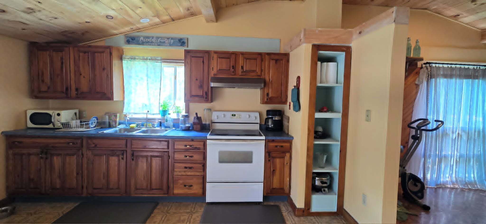 Une cuisine avec des meubles de rangement en bois, une cuisinière, un four à micro-ondes et une machine à café.