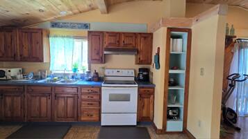 Une cuisine avec des meubles de rangement en bois, une cuisinière, un four à micro-ondes et une machine à café.