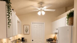 A kitchen with white cabinetry, a ceiling fan, a refrigerator, an oven, and a wooden floor. - Serene 3-bedroom 2 bathroom house with  pool and dining area-pet friendly (Lake Placid)