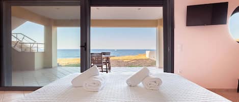 Une chambre d’hôtel avec un lit, une télévision et vue sur la plage.