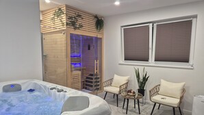 Une salle de bain moderne avec un jacuzzi, un lambris en bois, une douche en verre et deux fauteuils en osier.