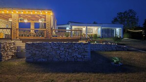 Une maison moderne dotée d’un patio en pierre, d’un espace salon extérieur et de guirlandes lumineuses.