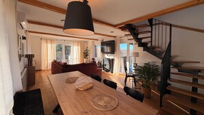 Un'ampia zona giorno con un tavolo da pranzo in legno, un divano e una scala.
