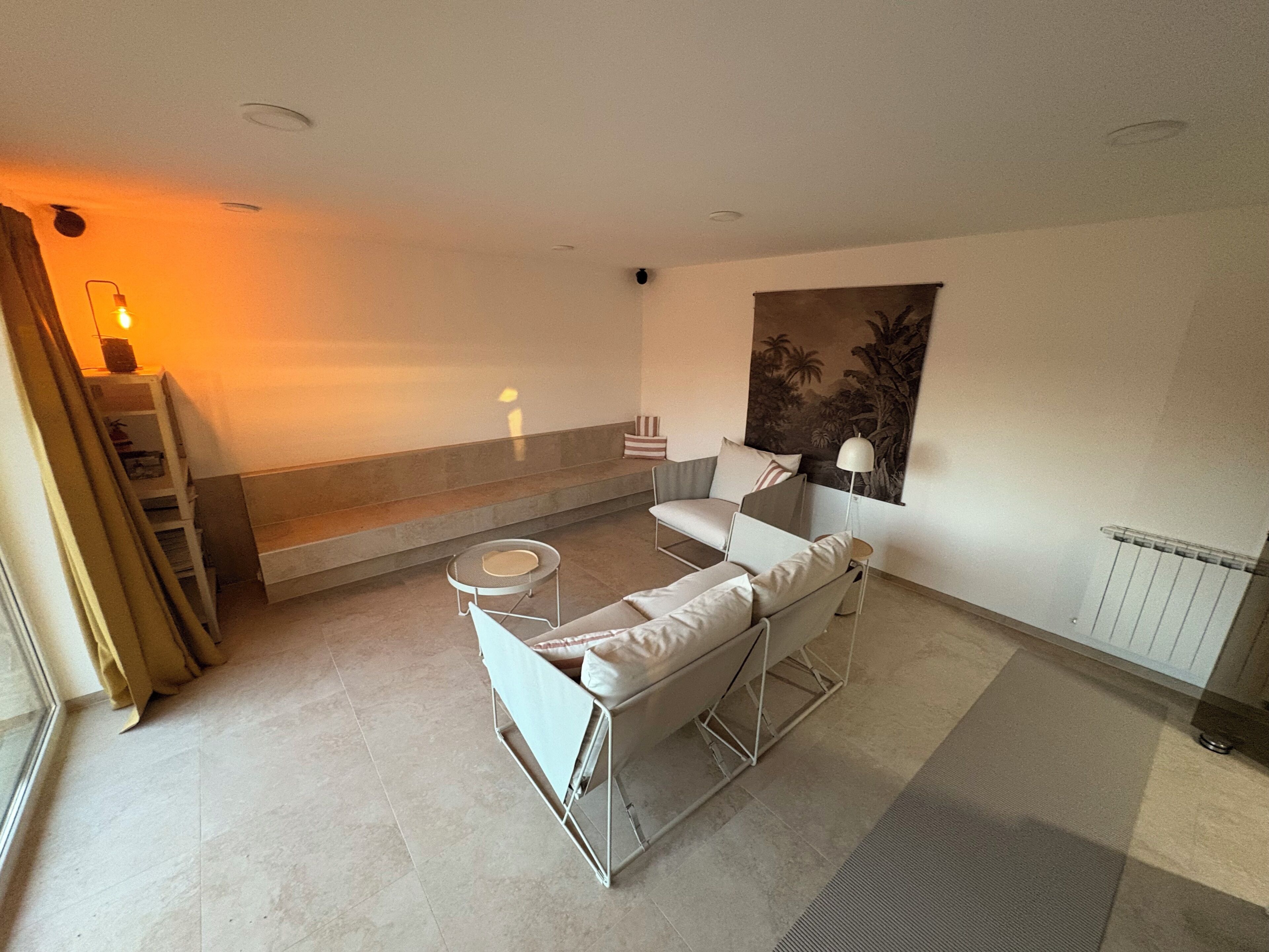 A modern living room with a sofa, a small round table, a floor lamp, and a painting on the wall.