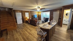 A spacious living area with a wooden staircase, a dining table with chairs, a sofa, and a ceiling fan. - Cozy Short Creek Cottage in welcoming Boaz with 2 BR AC for relaxing stays (Boaz)