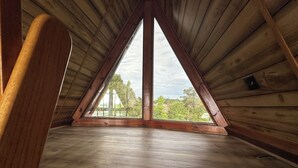 A triangular attic room with wooden walls and a sloped ceiling. - Cozy Short Creek Cottage in welcoming Boaz with 2 BR AC for relaxing stays (Boaz)