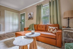 Ein Wohnzimmer mit einem braunen Ledersofa, zwei Marmortischen, einer Lampe und einer Tür mit grünem Türrahmen.