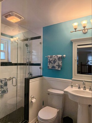 Une salle de bain avec une douche à parois de verre, des toilettes, un lavabo et un miroir.
