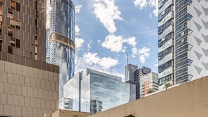 Een modern stadsbeeld met wolkenkrabbers, waaronder een opvallende glazen constructie en een gebouw met een geometrisch gevelontwerp.