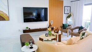 Una sala de estar moderna con un televisor de pantalla plana, un sofá, una mesa de centro y una silla.