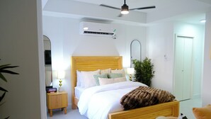 Un dormitorio con una cama de madera, mesitas de noche, un espejo y un equipo de aire acondicionado.