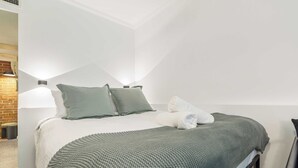 A neatly made bed with pillows, a blanket, and a folded towel. - Stylish studio apartment opposite Carlton Gardens (Carlton)