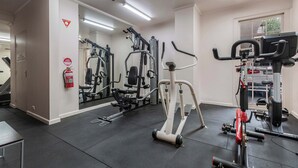 A gym with exercise equipment, a fire extinguisher, and a mirror on the wall. - Stylish studio apartment opposite Carlton Gardens (Carlton)