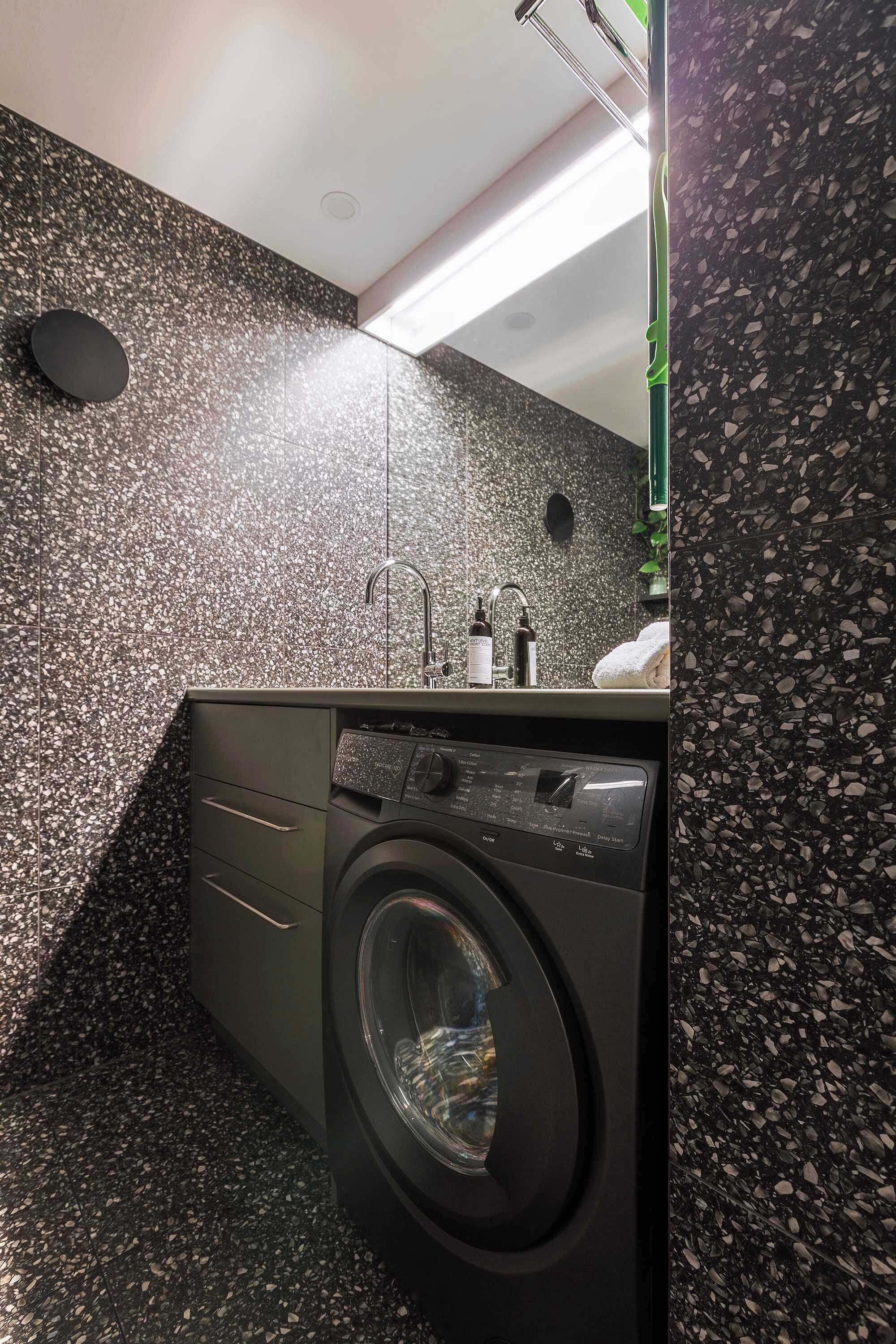 Ein modernes Badezimmer mit Waschmaschine, Waschbecken und Spiegel.