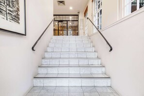 A marble staircase with metal handrails, leading to a door with a decorative metal gate. - Stylish studio apartment opposite Carlton Gardens (Carlton)