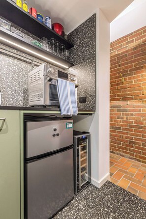 Eine kompakte Küche mit Mikrowelle, kleinem Kühlschrank und integriertem Backofen.