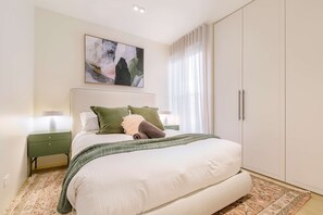 Een slaapkamer met een bed, nachtkastjes, een schilderij en een kledingkast.