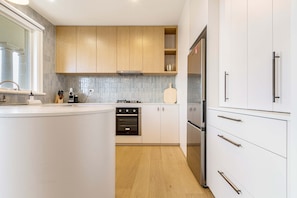 A modern kitchen with white cabinets, a stainless steel refrigerator, and a wooden countertop. - Stylish, Spacious Apartment in Malvern (Malvern)