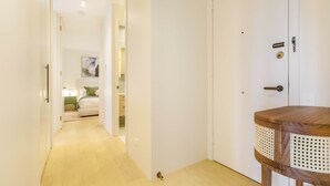 A hallway leading to a bedroom with a bed, a bedside table, and a door with a handle. - Stylish, Spacious Apartment in Malvern (Malvern)
